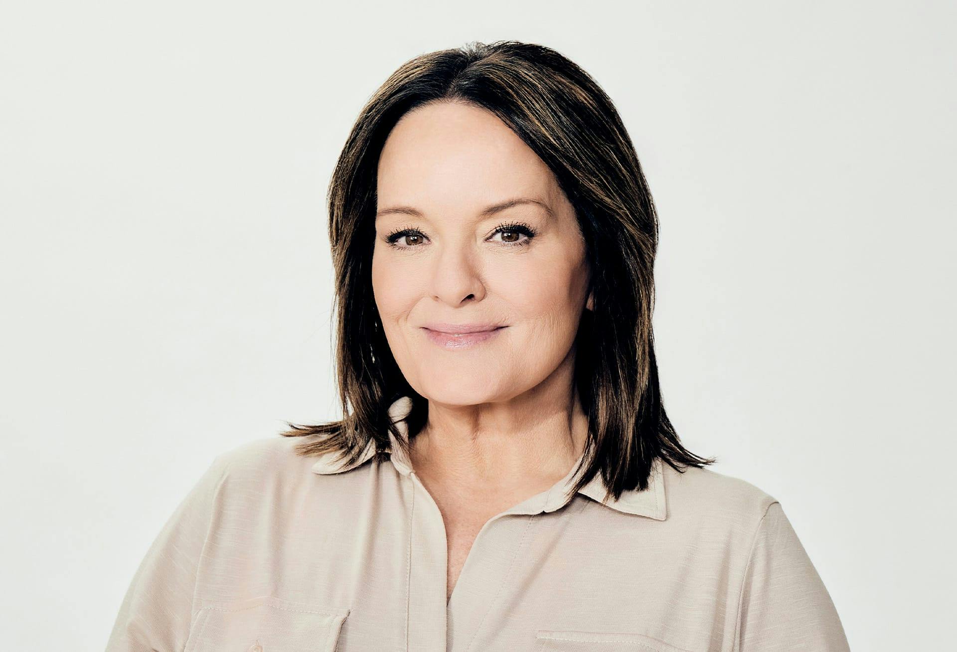 A woman with long hair and a beige shirt.