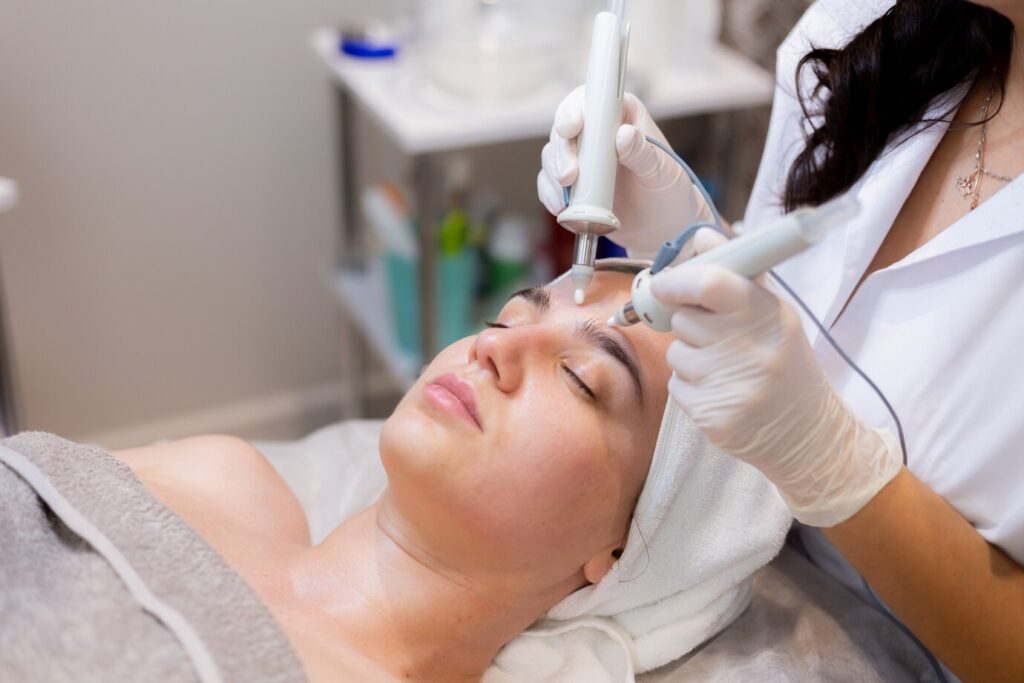 A woman getting her face cleaned by an esthetician.